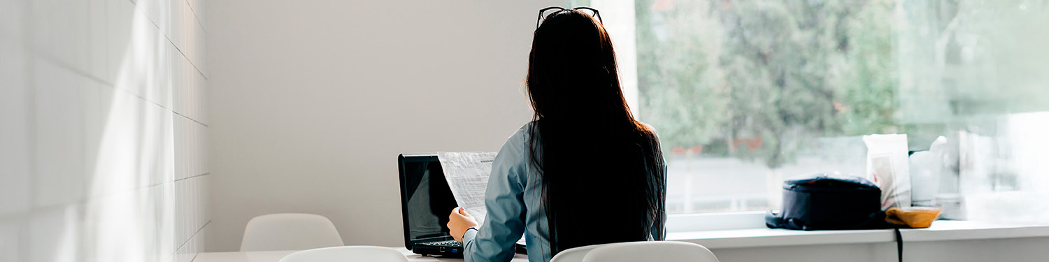 Frau sitzt vor Laptop mit dem Rücken zu uns – Beitrag zu Unterschied zwischen quantitativer und qualitativer Marktforschung